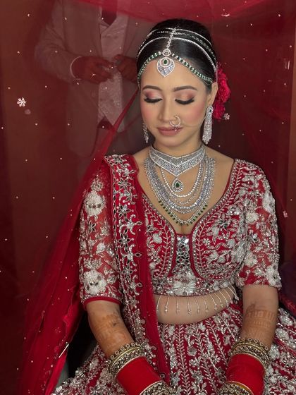 Seated with grace, this bride's silver and red lehenga is paired with a clean, elegant makeup look that focuses on glowing skin and defined eyes.