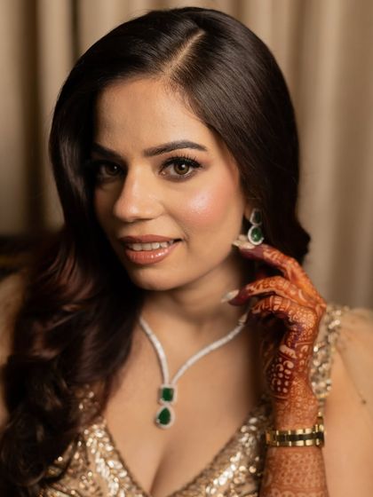 A close-up portrait of Ashima, highlighting her flawless skin and the elegant emerald necklace.