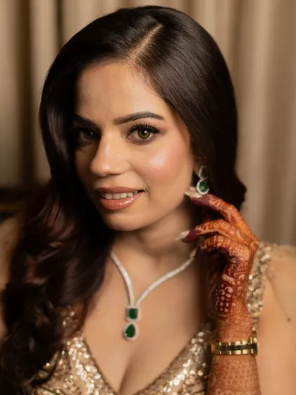 A close-up portrait of Ashima, highlighting her flawless skin and the elegant emerald necklace.