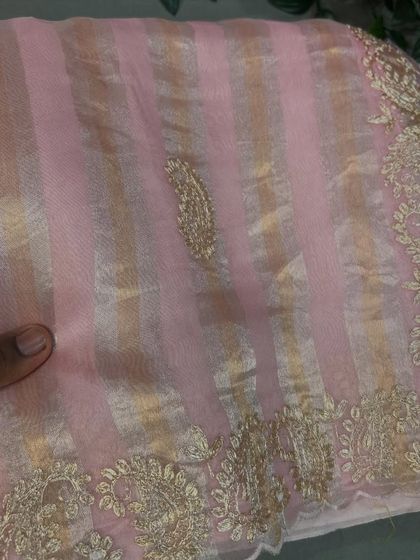A lovely pastel pink tissue stripes organza saree with a paisley motif and gold embroidery on the border.