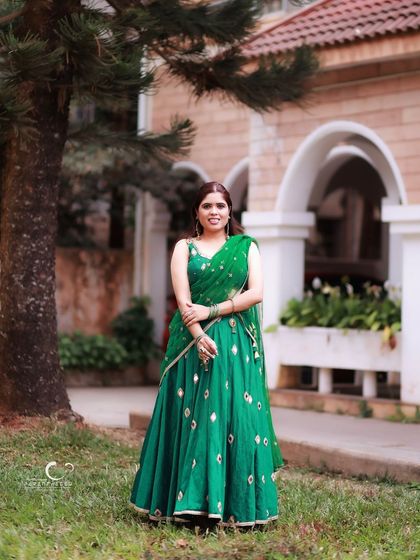 An elegant full-length portrait in a green traditional outfit, set in a beautiful garden. The natural light and surroundings add to the grace of the shot.