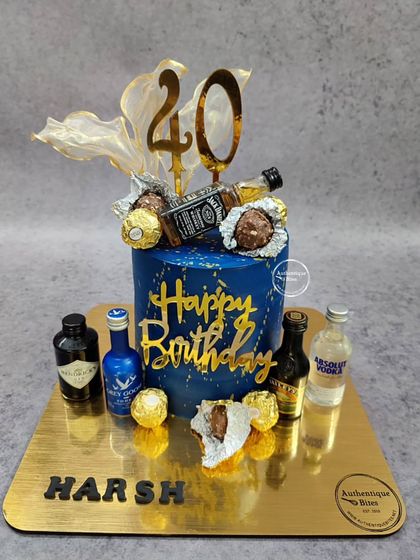 A fun and lavish cake for a 40th birthday. This royal blue cake is decorated with miniature bottles of Jack Daniel's, Grey Goose, and Absolut, along with Ferrero Rocher chocolates.