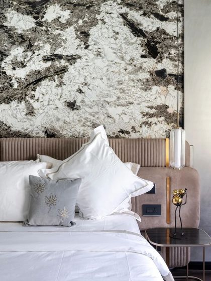 A dramatic slab of black and white marble serves as a headboard, turning the bed into a stunning focal point of the room.