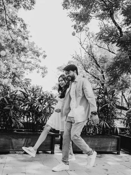A playful, candid moment of a couple walking, captured in black and white. The monochrome effect adds a classic, storytelling feel to this joyful image.