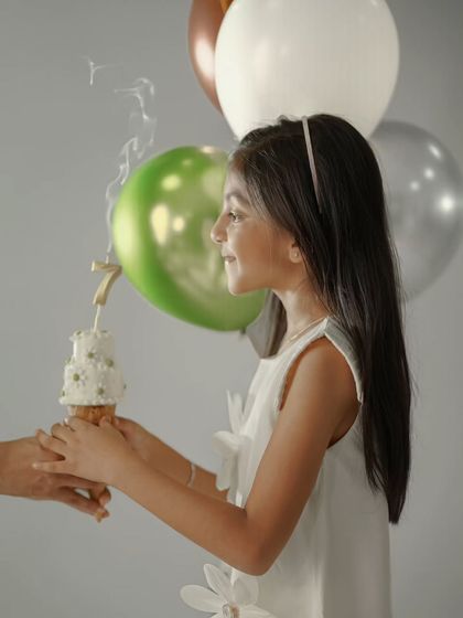 Making a wish on a tiny birthday cake. This candid shot captures a classic birthday tradition in a beautifully lit profile view.