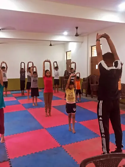 I lead a class of young children through a warm-up stretching routine.