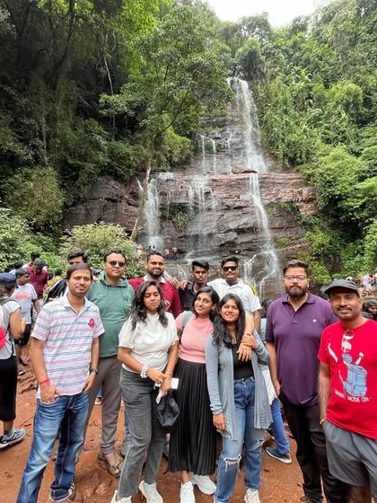 A happy group of travelers posing in front of Jhari Falls in Chikmagalur. Our trips are all about creating such joyful memories.