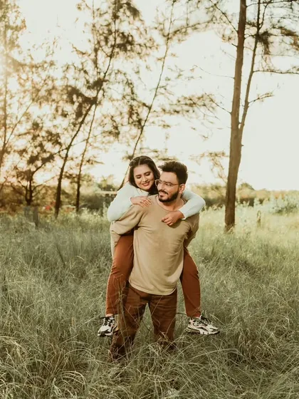 A fun piggyback ride in a grassy field, capturing a moment of pure, unscripted joy. We believe these playful moments are an essential part of any love story.