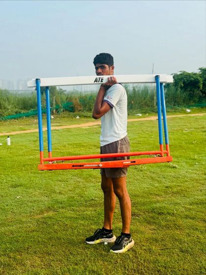 An athlete carries a hurdle as part of a strength and conditioning drill. This builds functional strength specific to the demands of a hurdler.