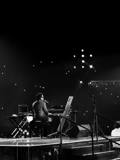 A solitary moment of A.R. Rahman on stage against a backdrop of thousands of phone lights. This image captures the profound connection between the artist and his audience that we strive to facilitate.