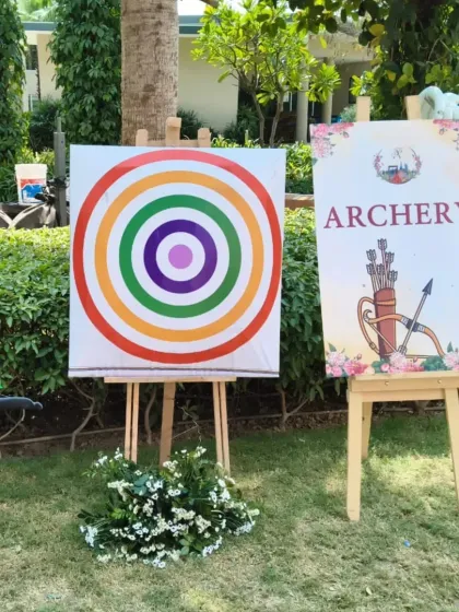 An archery game station with a target and signage, set up for a Haldi function. This offers a unique and skillful activity for guests to try.