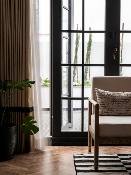 A detail shot of the living area, showing the herringbone wood floors and the custom-framed French doors that open to the patio. The design emphasizes natural light and a seamless indoor-outdoor connection.