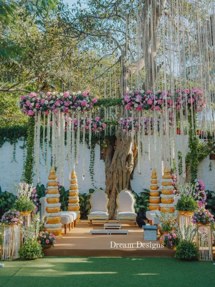A traditional mandap design featuring lotus-inspired pillars and a canopy of pink and white flowers. The hanging floral strings add texture and movement, creating a classic and beautiful ceremony space.