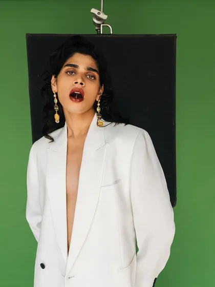A behind-the-scenes style shot from the Amama Jewels campaign. The image captures a candid, expressive moment while still showcasing the product against the studio setup.