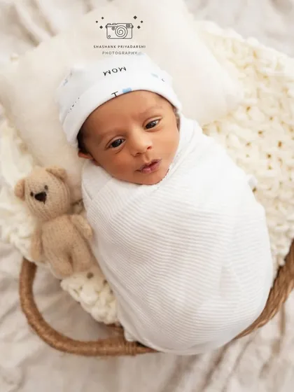 Another shot of an awake newborn, swaddled and cozy in a basket with a small teddy bear. These expressive moments are just as precious as the sleepy ones.