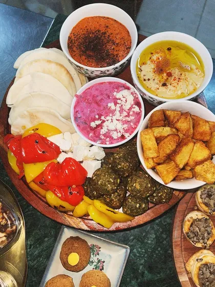 A classic Mezze Platter, perfect for sharing. This board includes our creamy hummus, muhammara, beetroot dip, falafel, pickled peppers, and warm pita bread.