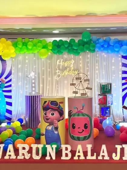 A rainbow-colored Cocomelon party with a striped backdrop and a full spectrum of balloons. The white picket fence adds a playful touch to the scene.