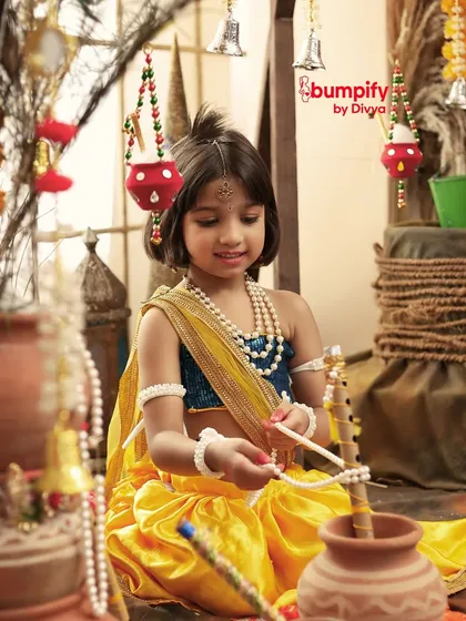 A candid moment of our little Radha playing with props during her Janmashtami photoshoot, her curiosity and innocence shining through.