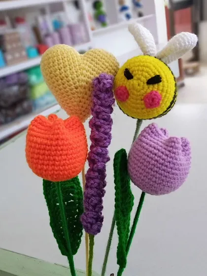 A playful and colorful selection of individual crochet stems. This small bunch includes an orange tulip, a purple tulip, a lavender sprig, a yellow heart, and a cute bumblebee.