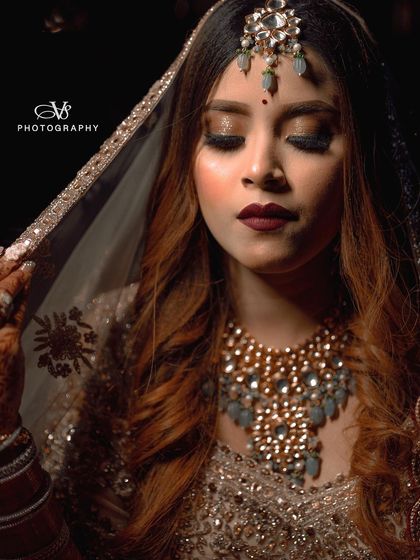 A stunning close-up of a bride, with a sheer, sparkling dupatta over her head, creating a soft and glamorous bridal portrait.