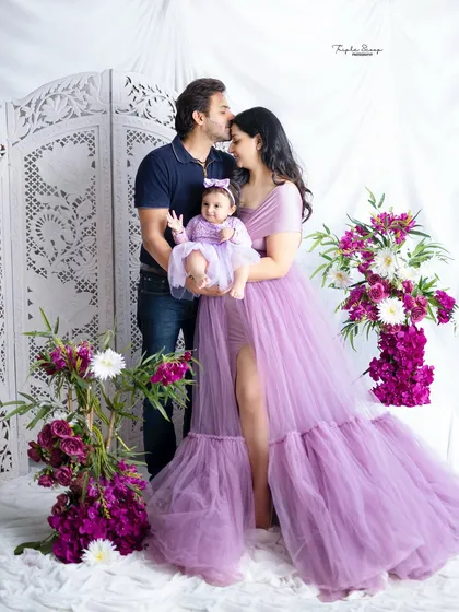 A classic family pose with a tender kiss from dad. The beautiful gowns and floral setup make this a truly special portrait.