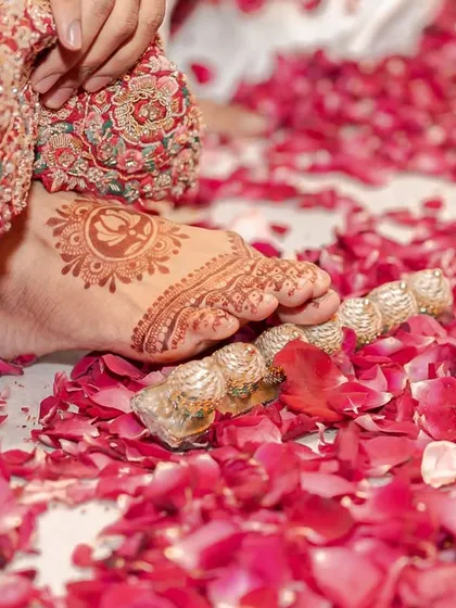 Sometimes the smallest details tell the biggest stories. A bride's feet, adorned with intricate mehendi and toe rings, step onto a bed of soft rose petals. It’s a poetic frame that signifies the beginning of her new journey.