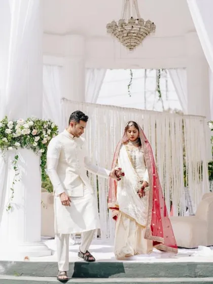 A beautiful couple framed by the elegant white drapes and floral arrangements of their daytime wedding ceremony.