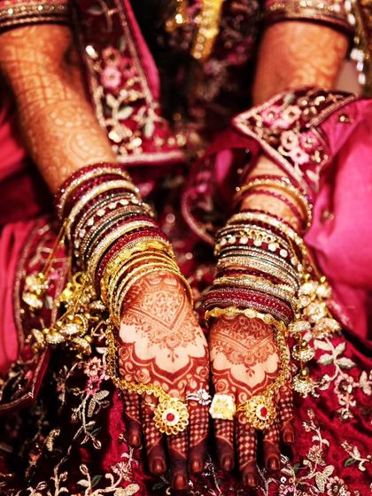 The bride's hands adorned with traditional jewelry, highlighting the beautiful, dark mehendi stain.