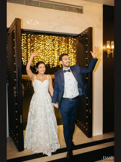 The grand entrance to their reception party, waving to friends and family with big smiles.