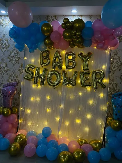 A view of the baby shower backdrop with the lights dimmed to emphasize the warm glow of the fairy lights. This creates a soft and inviting atmosphere for the event.