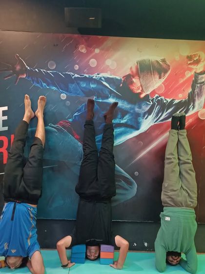 Students using yoga blocks to support their headstands (Sirsasana). Blocks provide stability and reduce pressure on the neck, making inversions more accessible.