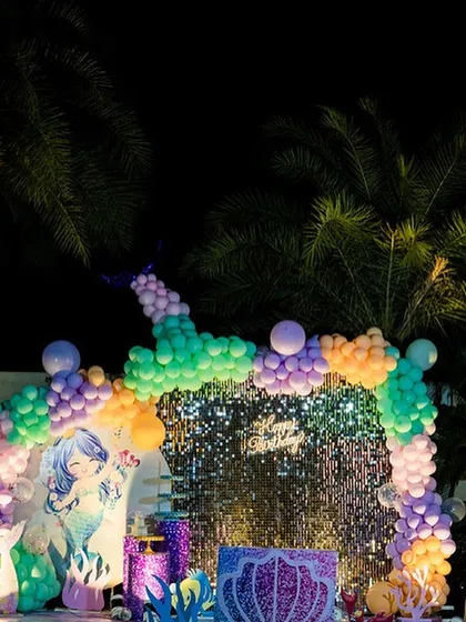 A magical Mermaid theme party setup for an outdoor celebration. This image shows the full scene with a shimmer wall, a custom mermaid backdrop, and a colorful balloon arch creating an under-the-sea atmosphere.