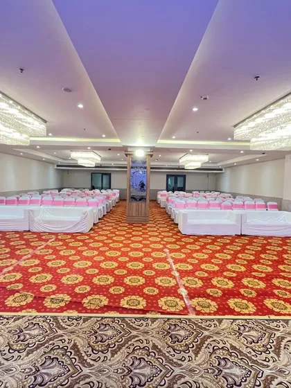 A full view of the Grand Golden Banquet in Vashi, showing the spacious hall with a red patterned carpet and elegant chandeliers.