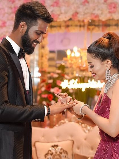 A joyful and candid moment as the couple exchanges rings during their engagement ceremony, with smiles that light up the room.