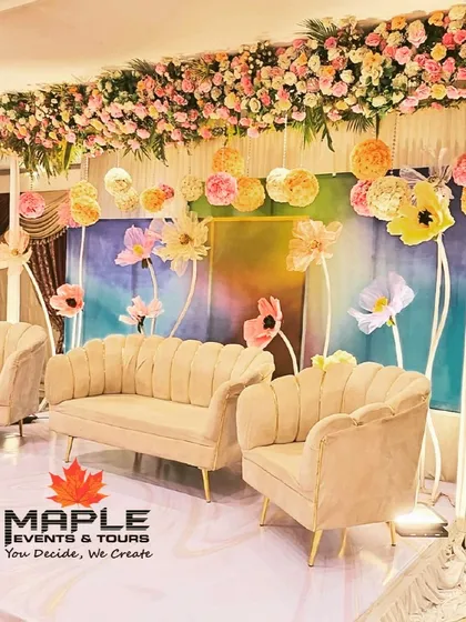 A whimsical and artistic stage with a pastel watercolor backdrop and oversized paper flowers. This creative and colorful setup is perfect for a daytime event or a couple looking for something unique and playful.