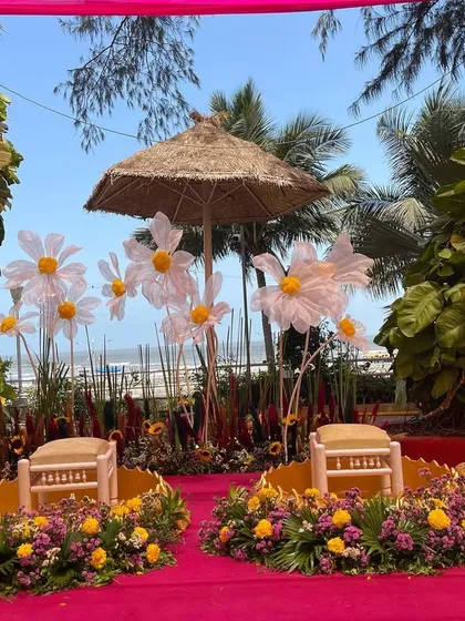 A unique Haldi seating arrangement with giant daisies and a thatched umbrella. This whimsical setup by the beach adds a playful and creative touch to the ceremony.