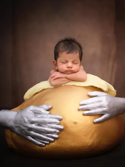 A truly personal and unique portrait, this newborn sleeps atop a golden cast of their mother's pregnant belly, a beautiful way to connect the journey of pregnancy and birth.