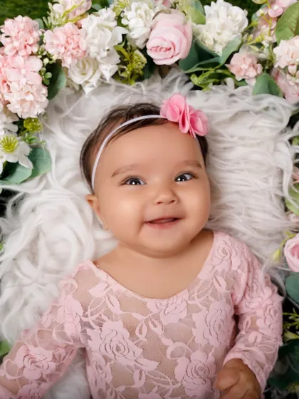 A perfect portrait of a smiling baby girl, nestled in a wreath of soft pink and white flowers. These are the smiles I live to capture.