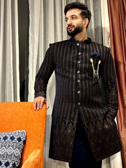 A different angle of the pinstriped Indo-Western sherwani, highlighting the texture of the fabric and the elegant brooch accessory.