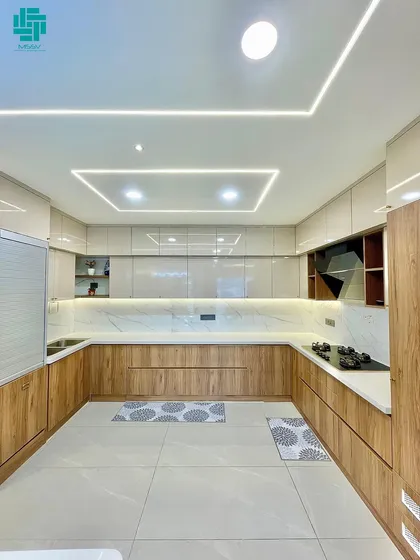 A modern U-shaped modular kitchen designed for ultimate functionality. Notice the seamless blend of wood-tone and high-gloss cabinets, complemented by integrated profile lighting for a bright and efficient cooking space.