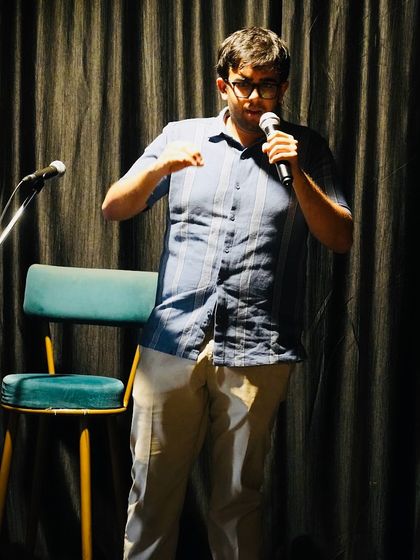 A comedian engages the crowd during his set. The lighting and stage setup at Karmasthan are perfect for creating a classic comedy club atmosphere for our open mic nights.