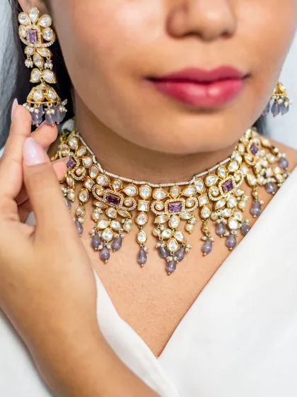 A close-up of a beautiful kundan choker with purple stone accents and pearl droppings. This piece adds a unique touch of color to a traditional design.