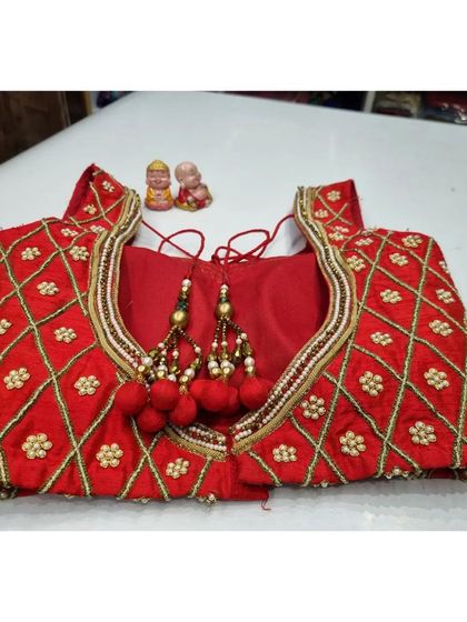 The finished red blouse with its diamond-pattern work and matching red tassels, ready for the client.