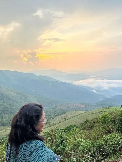 A quiet moment of reflection overlooking the rolling hills of Chikmagalur. The views from the top are a perfect reward after a refreshing trek with the group.