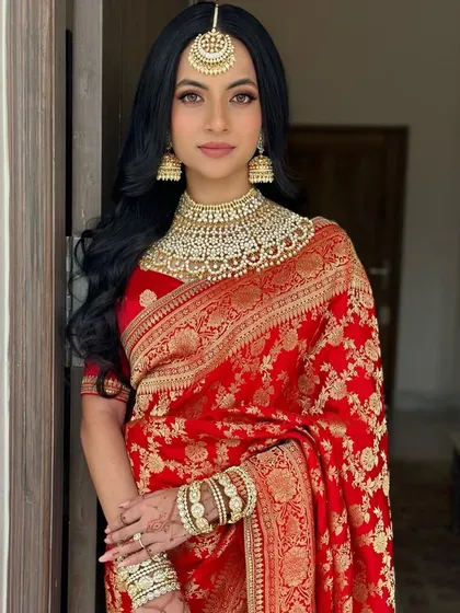 For a timeless and royal bridal look, I styled these classic, soft waves to complement a traditional red Sabyasachi saree. The hairstyle is designed to beautifully frame the face and accommodate a maang tikka, creating an iconic wedding day appearance.