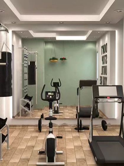 A compact and motivational home gym we designed. The space includes a treadmill, stationary bike, and a wall-mounted pull-up bar, with a full-length mirror to check form and a 'Don't Stop Until You're Proud' decal for inspiration.