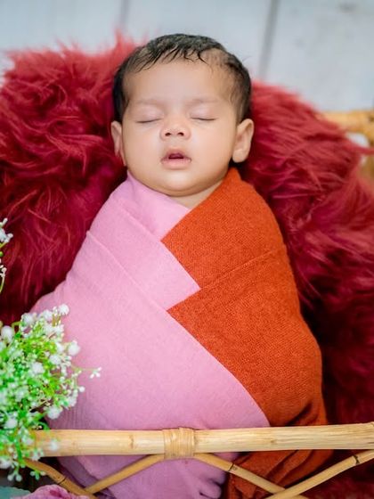 I love playing with complementary colors in my setups. Here, a two-toned pink and orange wrap adds a warm, gentle pop of color to this cozy basket portrait, complemented by delicate baby's breath flowers.