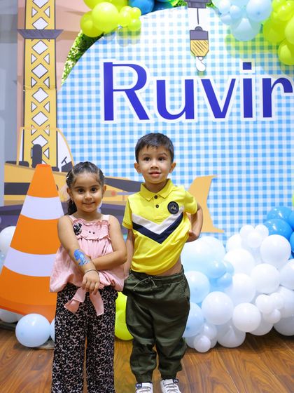 Two friends pose in front of the "Under Construction" backdrop. The bright colors and fun graphics make for a great photo spot.