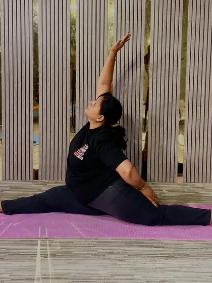 This is a seated wide-legged forward bend with a twist (Parivrtta Upavistha Konasana), an amazing pose for stretching the hamstrings, spine, and shoulders. It shows the kind of deep flexibility we work towards.