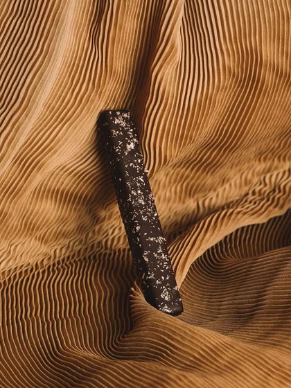 An artistic shot of a single Old School Fudge Stick, highlighting its sleek form and the texture of its chocolate coating.